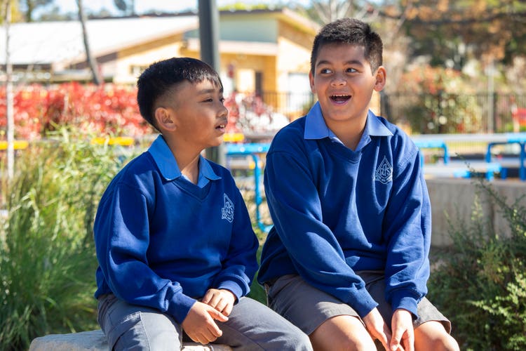 Two students sitting outside talking to each other