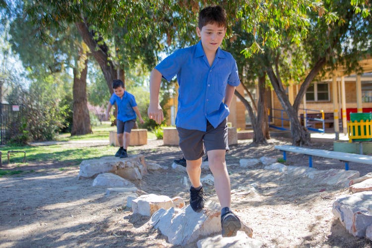 2 boys playing on the rocks in the exploratory playground area