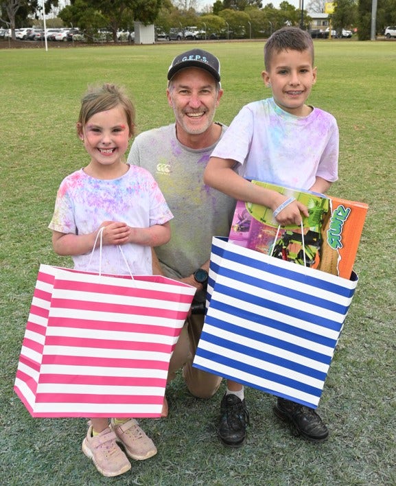 A picture of the principal with a boy and a girl smiling happily