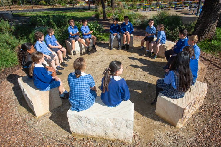 a class of students sitting outside in a yarning circle
