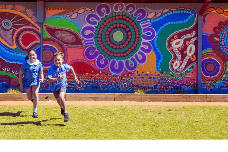 Two kids running away from a bright mural