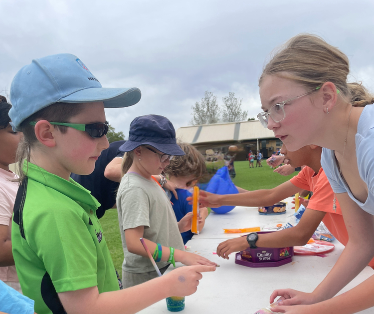 students standing near a table buying iceblocks from an older student.