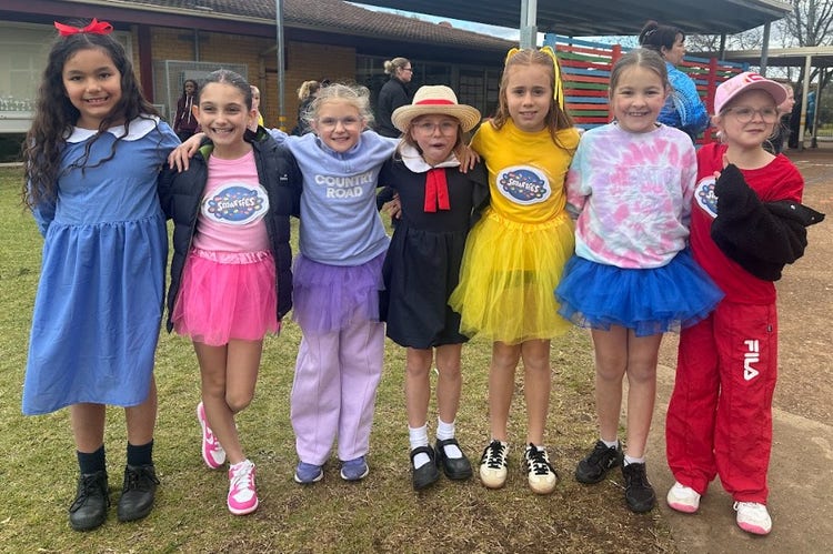7 students dressed bright and colourful all smiling at the camera.