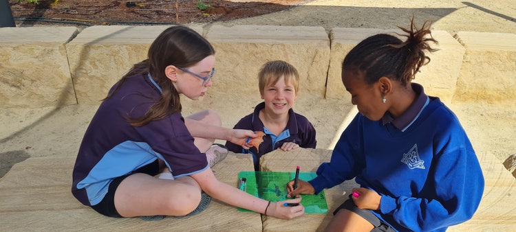 2 girls playing and 1 boy smiling at the camera.